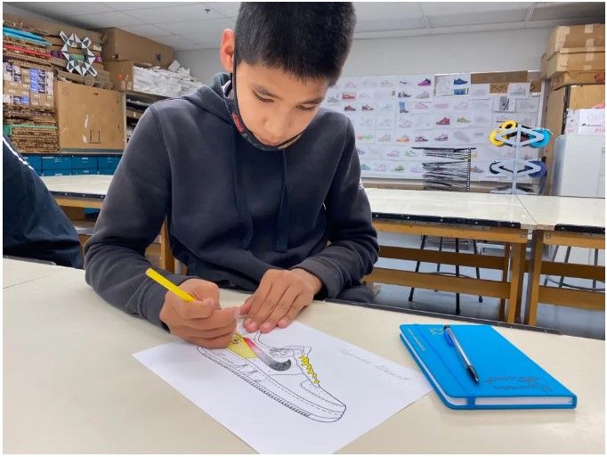 Norman Stewart, an eighth grade student, experiments with color blocking on a Nike sneaker worksheet during a course on brand design. Photo courtesy of Susan Wolfe