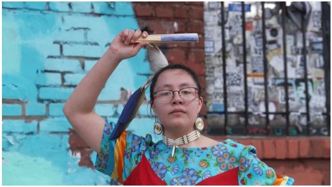 In this film still frame from “Closer Together,” Shandiin Kaline, a senior at Lame Deer High School, presents a dance of the Northern Cheyenne people, wearing traditional regalia, for a music video that will be released on May 7, at Refuge Gallery in Basin, Mont. / Photo courtesy of Pete Tolton