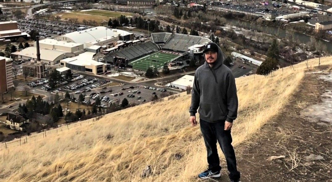 Victor Three Irons enjoyed hiking the trails in and around Missoula when he lived there. Victor stands high on one of the mountains that overlook the University of Montana Campus. / Photo by Tessa Passes