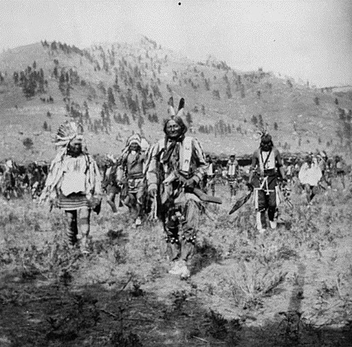 Sitting Bull, Rain In The Face, and John Grass stand in view of the Pryor Gap where the dancing took place during the Sitting